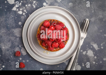 Vegane Pfannkuchen mit Himbeeren und Chia Samen auf eine graue Platte, dunklen Hintergrund, Ansicht von oben. Gesunde vegane Ernährung Konzept. Stockfoto