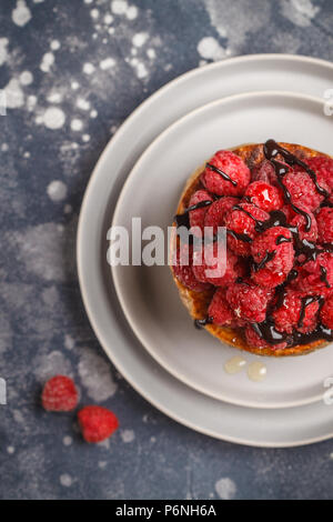 Vegane Pfannkuchen mit Himbeeren und Chia Samen auf eine graue Platte, dunklen Hintergrund, Ansicht von oben. Gesunde vegane Ernährung Konzept. Stockfoto