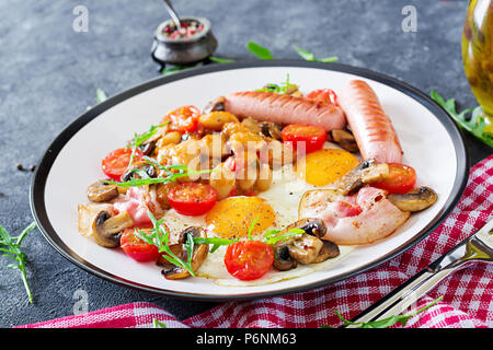 Englisches Frühstück - Spiegeleier, Bohnen, Tomaten, Champignons, Speck und Würstchen. Leckeres Essen. Stockfoto