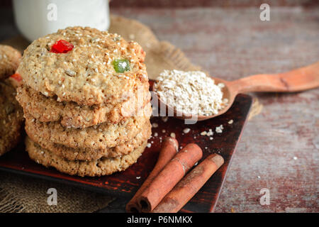Haferflocken Cookies, Zimtstangen und Milch auf einem Holztisch Stockfoto