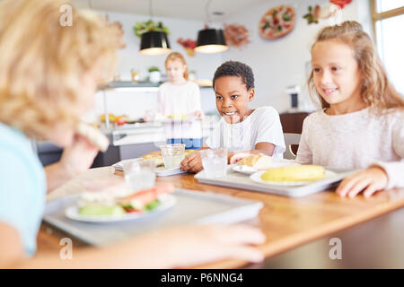 Glückliche Kinder gemeinsamen Mittagessen in der Schulkantine Stockfoto