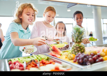 Hungrige Kinder als Schüler abholen Obst am Buffet in der Cafeteria Stockfoto