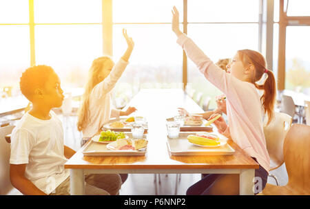 Kinder mit Mittagessen in der Kantine der Schule tun hohe fünf mit ihren Händen Stockfoto