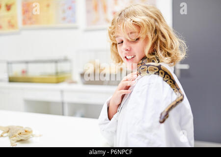 Junge mit einer Schlange auf seiner Schulter in der Biologie. Grundschule Lehre Stockfoto