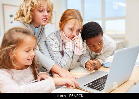 Schüler der Grundstufe in einer Arbeitsgruppe gemeinsam mit dem Laptop. Stockfoto