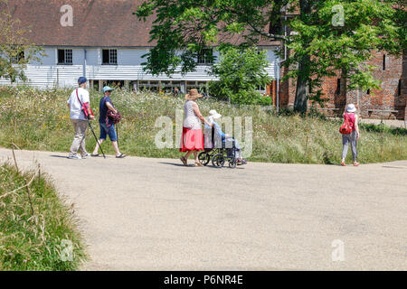 Besucher kommen zu den Sissinghurst Castle Gärten an einem langen Sommertag. Von einem öffentlichen Reitweg, Kent, Großbritannien Stockfoto