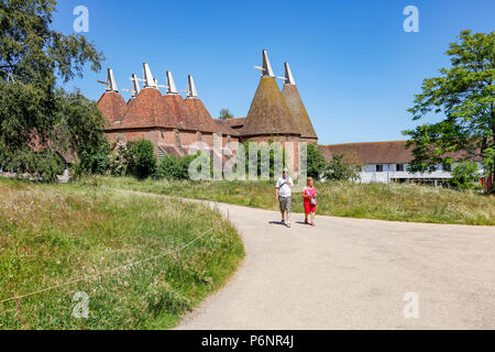 Besucher kommen zu den Sissinghurst Castle Gärten an einem langen Sommertag. Von einem öffentlichen Reitweg, Kent, Großbritannien Stockfoto