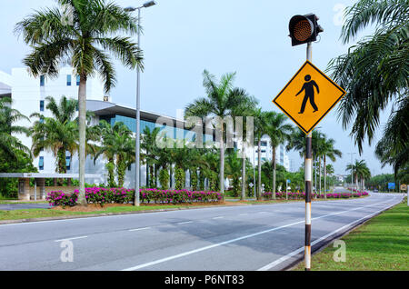 Fußgängerüberweg Schild mit roter Ampel, leere Stadt Straße mit Palmen und Blumen, asphaltierte Straße mit Markierungen Stockfoto