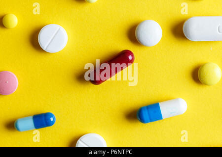 Verschiedene Tabletten und Kapseln auf gelbem Hintergrund verstreut, Platz für Text Stockfoto