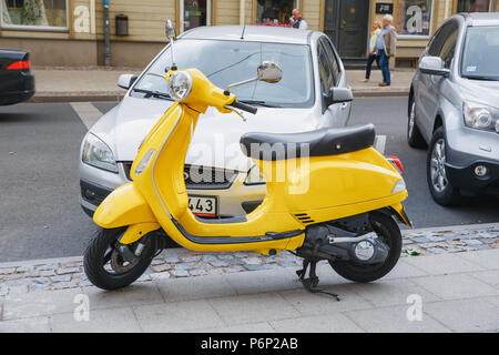 Stadt Riga, Lettland. Retro Scooter Vespa an Street, Farbe gelb. Stadtentwicklung Blick auf die Stadt. 2018. Stockfoto