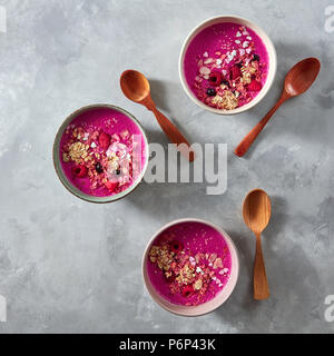 Eine gesunde Smoothie aus Rüben, Himbeeren, Johannisbeeren und Haferflocken in Platten mit Holzlöffel auf grauem Beton Hintergrund mit Kopie Raum gemacht. Top Stockfoto