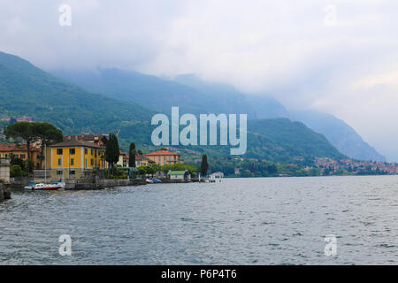 Comer see und Gebäude auf Küste und Alpen Berg mit Wolken im Hintergrund. Stockfoto