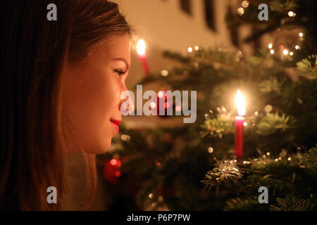 Mädchen betrachten eine Kerze auf einem Weihnachtsbaum. Genf. Die Schweiz. Stockfoto