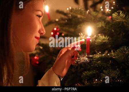 Mädchen betrachten eine Kerze auf einem Weihnachtsbaum. Genf. Die Schweiz. Stockfoto