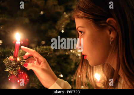 Mädchen betrachten eine Kerze auf einem Weihnachtsbaum. Genf. Die Schweiz. Stockfoto