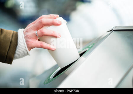 Frau mit Mülltrennung Container wegwerfen Kaffeetasse Stockfoto