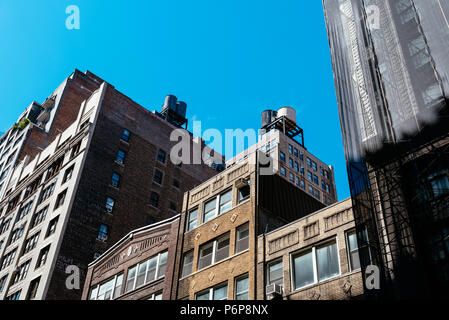 New York City, USA - 20. Juni 2018: Low Angle View der alten Gebäude und Wassertürme gegen Himmel in Midtown Manhattan Stockfoto