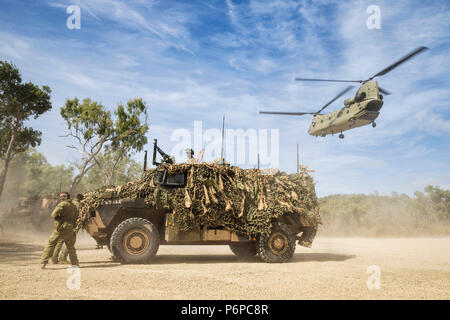 Soldaten nehmen Deckung hinter einem Bushmaster Protected Mobilität Fahrzeug als CH-47 Chinook aus liftanlagen der Shoalwater Bay Training Bereich im Norden von Queensland während der Übung Hamel 2018. Die US-amerikanischen Soldaten aus dem ersten Bataillon, 293 Infanterie Regiment, 76th Infantry Brigade Combat Team, Indiana National Guard, zusammen mit australischen Soldaten vom 7. Brigade in der Shoalwater Bay Truppenübungsplatz und durch eine Reihe von Schlachten und Engagements verschoben von Juni 18 - 27 Die australische Feuerwehr für die Bereitstellung zu zertifizieren und die jährliche Schulungsbedarf des Indiana National Guard battalio zu erfüllen Stockfoto