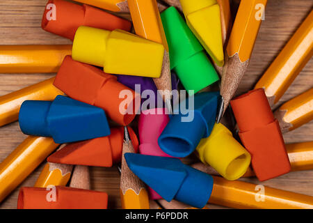 Mehrfarbige Bleistift Radierer und geschärft Bleistift Punkte in einem Stapel auf einem hölzernen Schreibtisch. Stockfoto