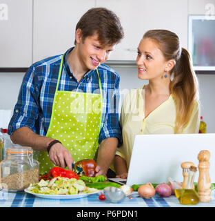 Junge Frau, kochen Mann etwas auf dem Laptop Bildschirm Stockfoto