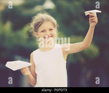 Glückliches Mädchen spielen mit einfachen Papierflieger Spielzeug an einem sonnigen Tag in der Stadt Stockfoto