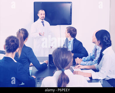 Positive lächelnde effiziente Wissenschaftler präsentieren Bericht während der Sitzung im Büro Stockfoto