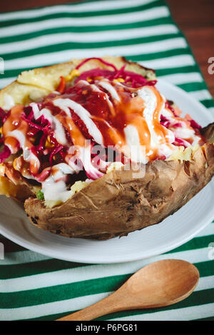 Kumpir, Türkische gebackene Kartoffeln mit Käse, Mais, Wurst, Ketchup, Mayonnaise und Oliven. Stockfoto