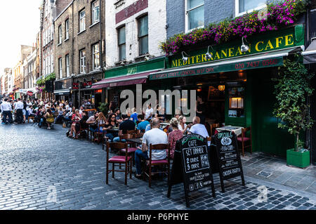 Reihe von Restaurants, in denen Kunden im Freien Speisen im Freien auf der gepflasterten Straße, Berwick Street, Soho, London, England, UK. Stockfoto