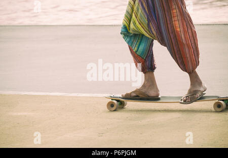 Hippy reiten ein Skateboard tragen Flip Flops/Sandalen. Stockfoto