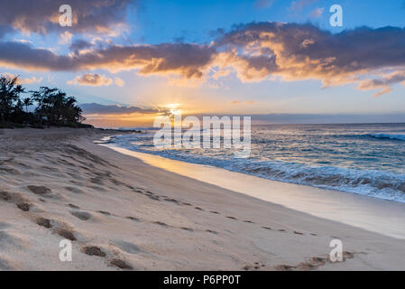 Sonnenuntergang über Sunset Beach auf der North Shore von Oahu, Hawaii mit surf Rollen in über Coral Felsen am Strand Stockfoto