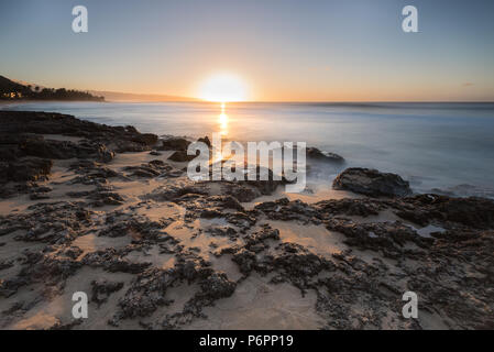 Nahaufnahme von Wellen in über bei Sonnenuntergang am Sunset Beach auf der North Shore von Oahu, Hawaii coral Rolling Stockfoto