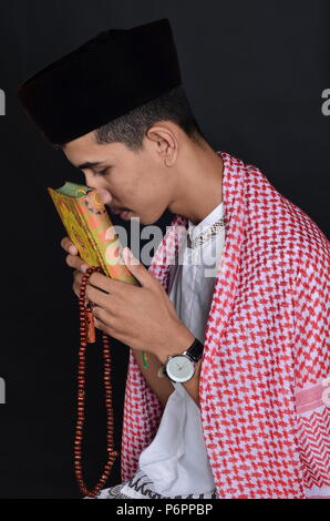 Jungen asiatischen muslimischen Mann mit Koran (Quran) Stockfoto