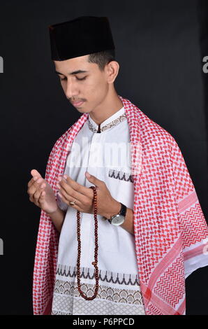 Jungen asiatischen muslimischen Mann, der betet mit gebetsperlen Stockfoto
