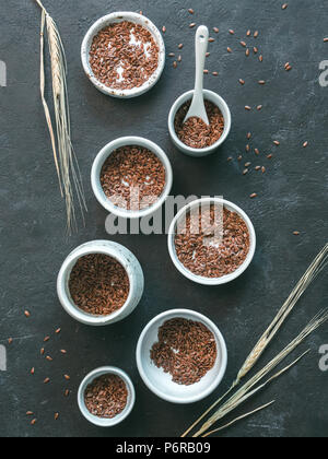 Leinsamen und trockenen Roggen Ohr auf dunklem Hintergrund. Der kleine Schalen mit organischer Leinsamen oder Leinen Saatgut. Leinsamen ist reich an Omega-3-Fettsäuren. Vert Stockfoto