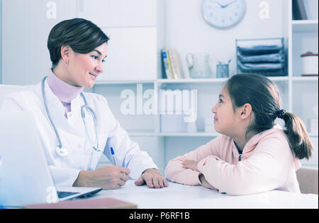 Arzt füllt die Karte des Patienten für Mädchen und fragt sie über Gesundheit in der Arztpraxis Stockfoto