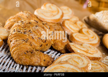 Nahaufnahme von frischen Croissant bestreut mit Sesam und Leinsamen auf Rattan mat mit anderen Backwaren Stockfoto