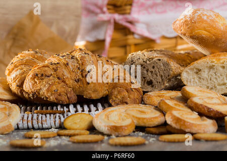 Sortiment an frischen Backwaren auf wicker Mat mit Korb auf hölzernen Hintergrund Stockfoto