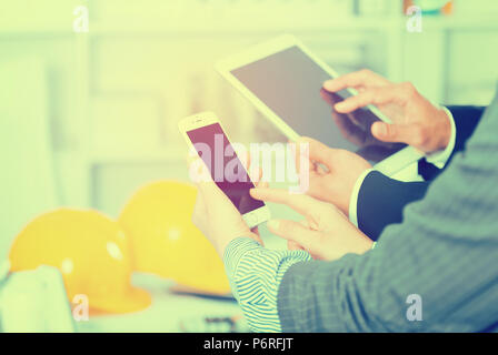 Hände von zwei Geschäftspartnern mit Geräten im Büro für Gestaltung Stockfoto