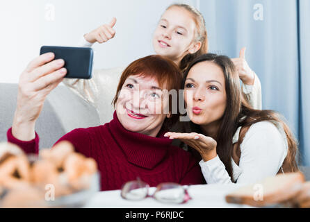 Gerne ältere Frau unter selfie mit ihrer erwachsenen Tochter und Enkelin zu Hause Stockfoto