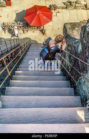 Ein Tourist steigt die steilen Treppen an der Tempelanlage Angkor Wat, Siem Reap, Kambodscha. Stockfoto