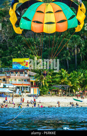 Parasailing über White Beach Touristen bei Puerto Galera, Oriental Mindoro, Philippinen. Stockfoto