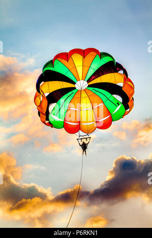 Parasailing über Weißen Strand mit blauem Himmel und bunten Wolken bei Puerto Galera, Oriental Mindoro, Philippinen. Stockfoto