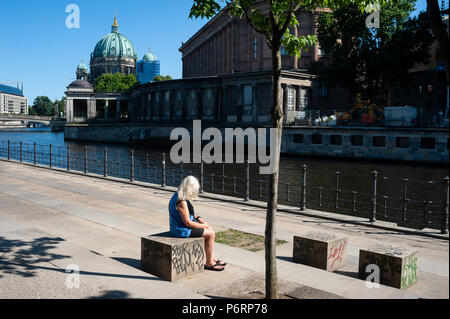 07.06.2018, Berlin, Deutschland, Europa - eine Frau sitzt am Ufer der Spree in der Berliner Mitte. Stockfoto