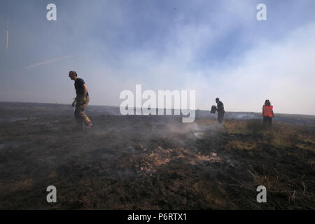 Feuerwehrmänner von Tyne und Feuer- und Rettungsdienst tragen Sie das Feuer auf Winter Hill in der Nähe von Bolton, als mehr als 20 Löschfahrzeuge an der Szene sind mit Crew die Bewältigung der Moorlandschaft Brände. Stockfoto