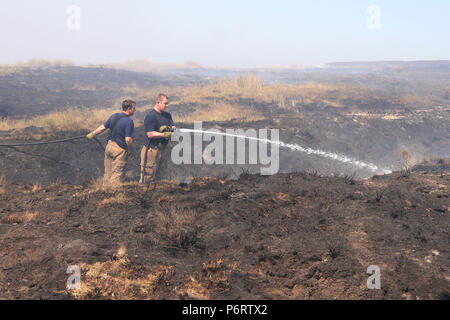 Feuerwehrmänner von Tyne und Feuer- und Rettungsdienst tragen Sie das Feuer auf Winter Hill in der Nähe von Bolton, als mehr als 20 Löschfahrzeuge an der Szene sind mit Crew die Bewältigung der Moorlandschaft Brände. Stockfoto