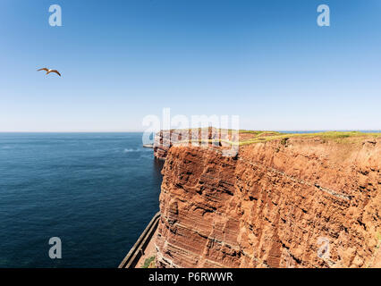 In rotem Sandstein, die Hohen Küste auf der Insel Helgoland gegen den blauen Himmel und Meer Stockfoto