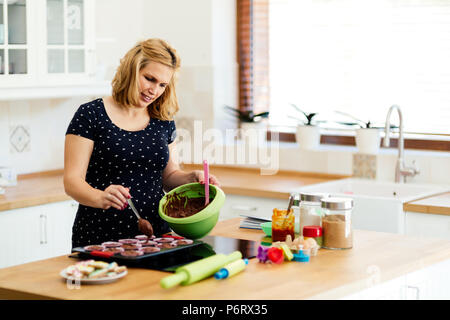 Schöne schwangere Frau Vorbereitung Muffins Stockfoto