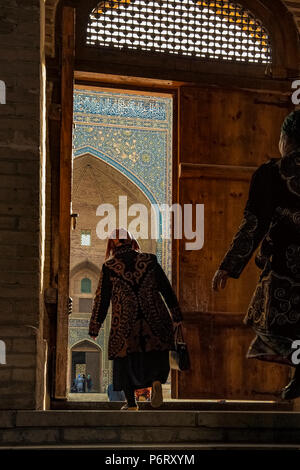 Alte Frauen von dem Tor der Moschee Kalon in Richtung der Medressa Mir-i-arabischen auf dem Hintergrund, Buchara, Usbekistan Stockfoto