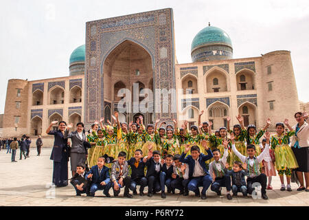 Eine Gruppe von Studenten auf Klassenfahrt in Buchara für die Navruz vor Kalon Moschee posiert mit dem medressa Mir-i-arabischen auf dem Hintergrund, Usbekistan Stockfoto