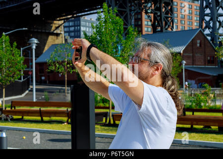 Mann mittleren Alters Brillen fotografiert Stadt mann Fotografieren auf dem Telefon Stockfoto